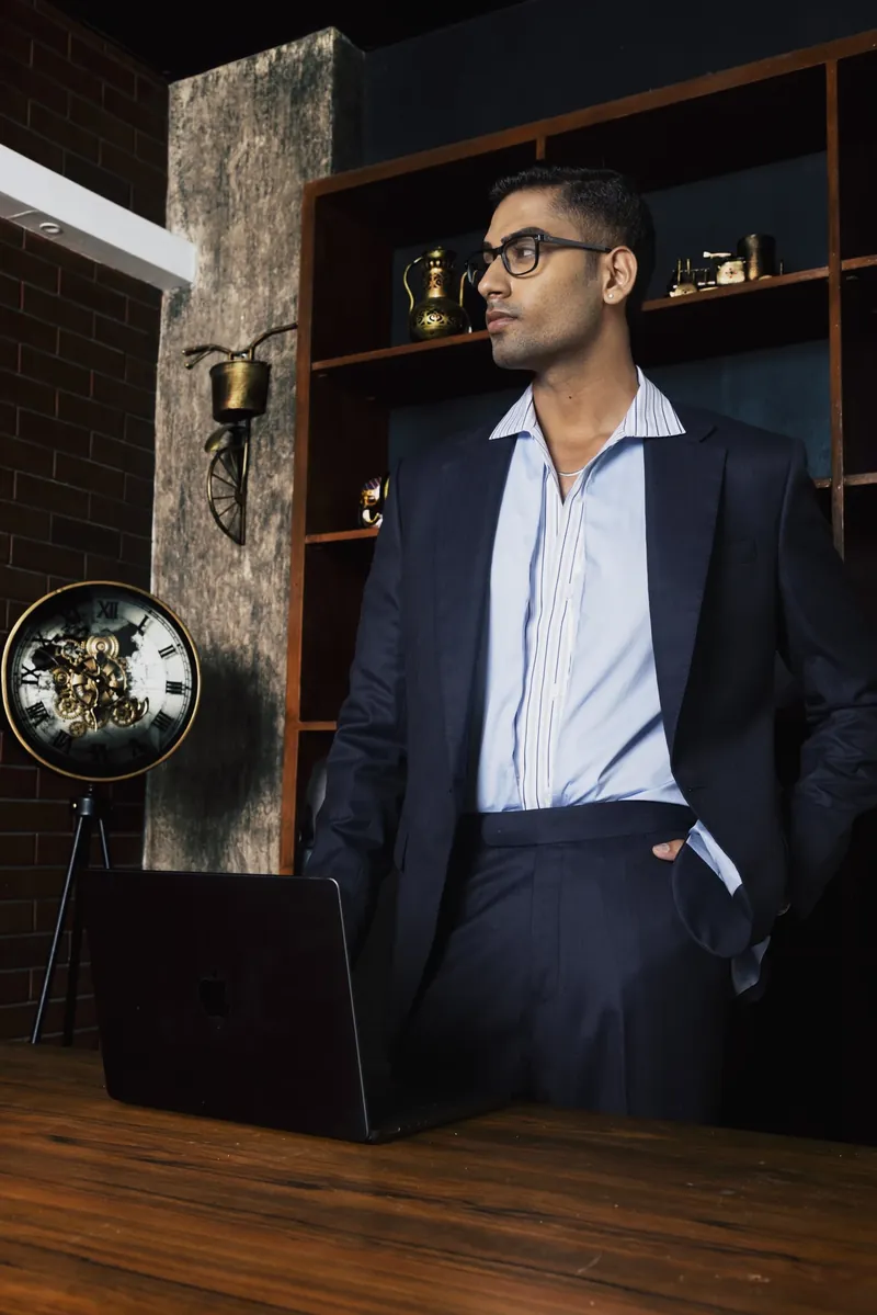 A navy suit in a lamplit study