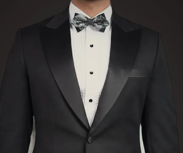 The lapel: Peak lapel faced in silk · one button, worn with a bow tie.